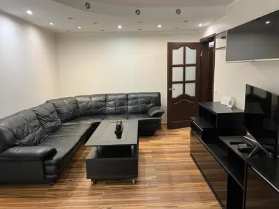 a living room with a black leather couch and a table at 2 kambarių butas Alytuje in Alytus