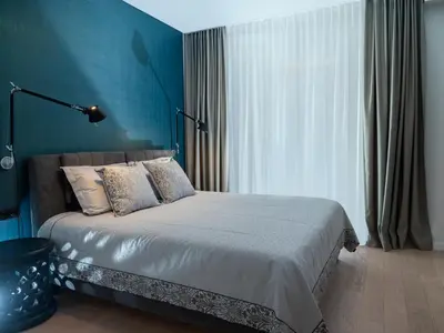 a bedroom with a bed with a blue wall at Butique Apartamentai Birštone - Holistic Skin & Wellness SPA Apartments - Inovatyvios dermatologijos centras in Birštonas