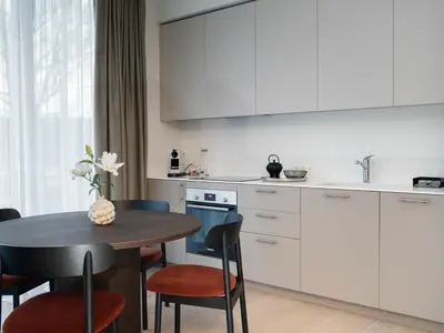 a kitchen with white cabinets and a table with chairs at Butique Apartamentai Birštone - Holistic Skin & Wellness SPA Apartments - Inovatyvios dermatologijos centras in Birštonas