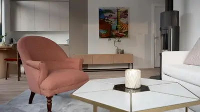 a living room with a chair and a table at Butique Apartamentai Birštone - Holistic Skin & Wellness SPA Apartments - Inovatyvios dermatologijos centras in Birštonas