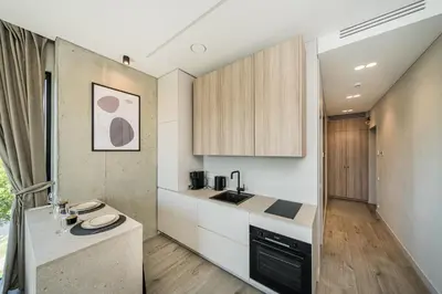 a kitchen with white counters and wooden cabinets at Kaunorama Riverside Suite in Kaunas