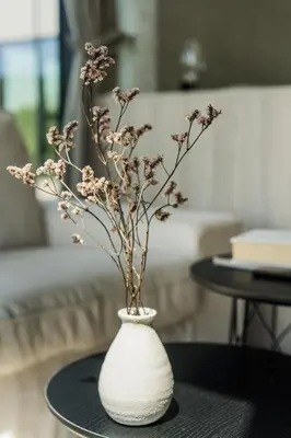 a white vase with flowers on a table at Kaunorama Riverside Suite in Kaunas