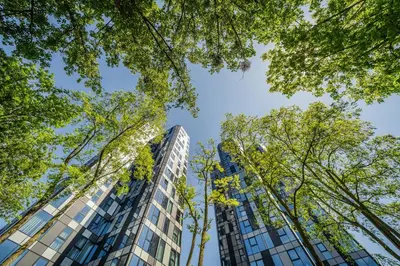 a tall building with trees in the foreground at Kaunorama Riverside Suite in Kaunas