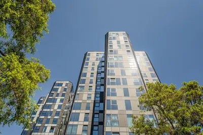 a tall building with trees in front of a blue sky at Kaunorama Riverside Suite in Kaunas