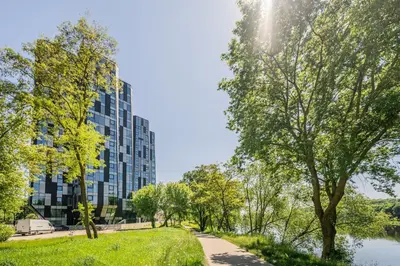a path in a park next to a tall building at Kaunorama Riverside Suite in Kaunas