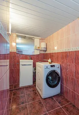 a washer and dryer in a red tiled bathroom at Spacious Studio apartment by Polo apartments in Kaunas