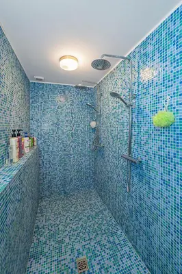 a bathroom with blue tiled walls and a shower at Spacious Studio apartment by Polo apartments in Kaunas