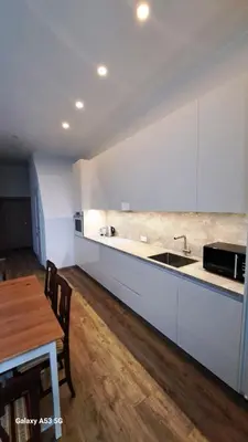 a kitchen with white cabinets and a wooden table at KaunasInn LA in Kaunas