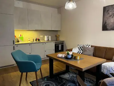 a living room with a table and a kitchen at Kauno Senamiestis in Kaunas