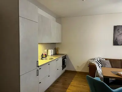 a kitchen with white cabinets and a sink and a table at Kauno Senamiestis in Kaunas