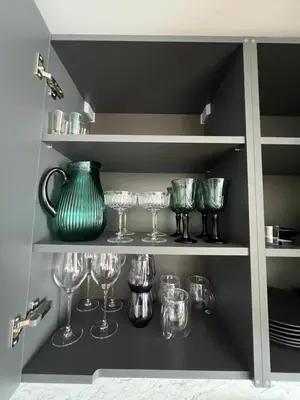 a shelf with wine glasses and a green vase at Hygge Apartments in Druskininkai