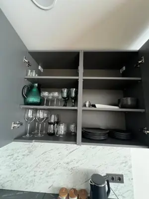 a kitchen shelf with plates and glasses on it at Hygge Apartments in Druskininkai