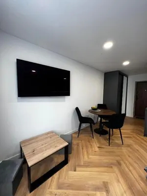 a living room with a table and a television on the wall at Hygge Apartments in Druskininkai