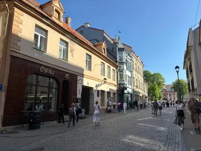 a group of people walking down a street with buildings at Barbacan Apartments in the Old Town in Vilnius