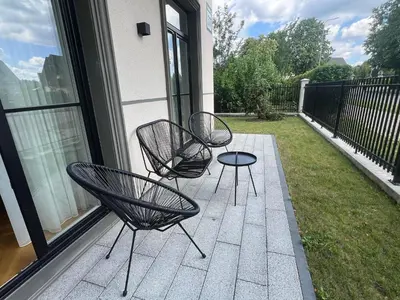 three black chairs and a table on a balcony at 2BD,Terrace, AC, next to Dineika Park, Brand NEW, by Cohost in Druskininkai