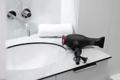 a blow dryer on a counter next to a sink at 2BD,Terrace, AC, next to Dineika Park, Brand NEW, by Cohost in Druskininkai