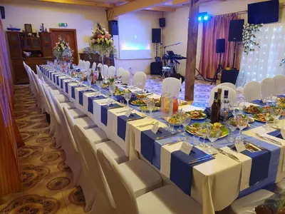 a long table with white and blue tables and chairs at Vila Dubysa in Milašaičiai