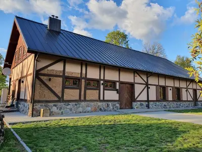 a barn with a black roof and a stone wall at Vila Dubysa in Milašaičiai