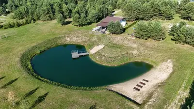 an aerial view of a pond on a hill with a house at Sodyba Azagis in Vilkanastrai
