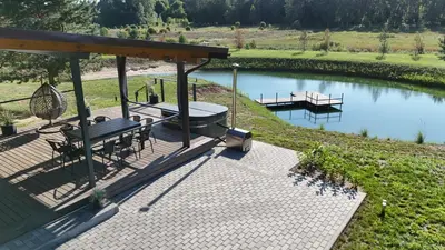 a deck with a table and chairs next to a river at Sodyba Azagis in Vilkanastrai