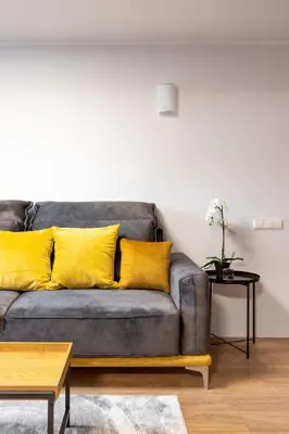 a living room with a gray couch with yellow pillows at Newly Refurbished Lukiskiu Square Apartment by Reside Baltic in Vilnius