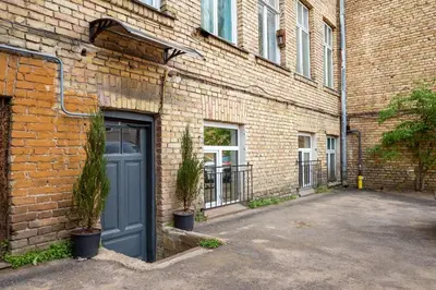 a brick building with a blue door and two plants at Newly Refurbished Lukiskiu Square Apartment by Reside Baltic in Vilnius