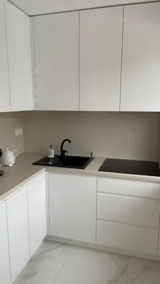 a white kitchen with a sink and white cabinets at Central Boulevard Apartment 2 in Šiauliai