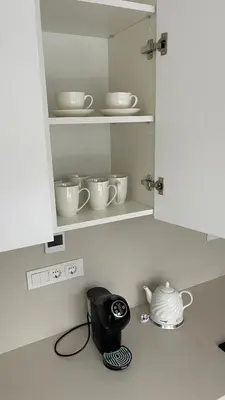 a kitchen counter with a cupboard with dishes and a tea kettle at Central Boulevard Apartment 2 in Šiauliai