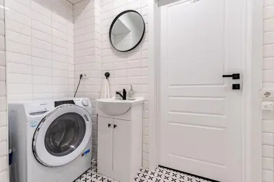 a white bathroom with a washing machine and a mirror at Modern flat in Old Town Kaunas - Parking & Self Check-In in Kaunas