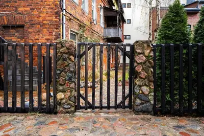 a black iron gate with a stone wall at Modern flat in Old Town Kaunas - Parking & Self Check-In in Kaunas