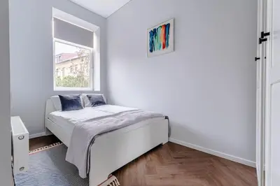 a white bedroom with a bed and a window at Modern flat in Old Town Kaunas - Parking & Self Check-In in Kaunas