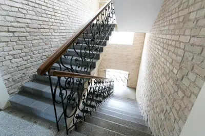a staircase with a wrought iron railing next to a brick wall at G-45 in Vilnius