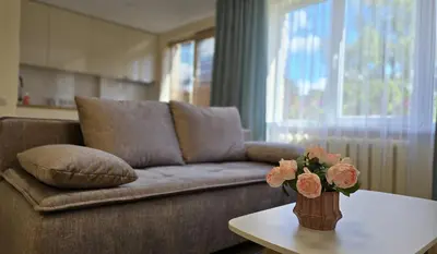 a living room with a couch and a table with flowers at Studio Anna in Panevėžys