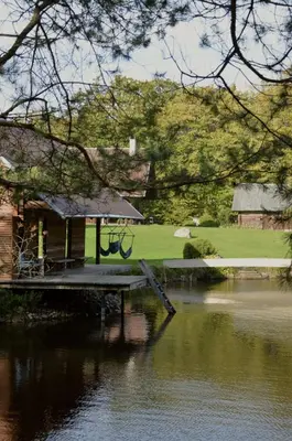 a house with a dock next to a body of water at Užukalnio sodyba in Užuguostis