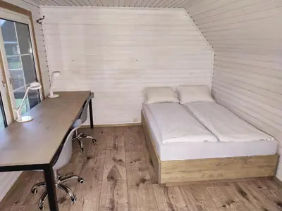 a small bed in a room with a desk at Užukalnio sodyba in Užuguostis