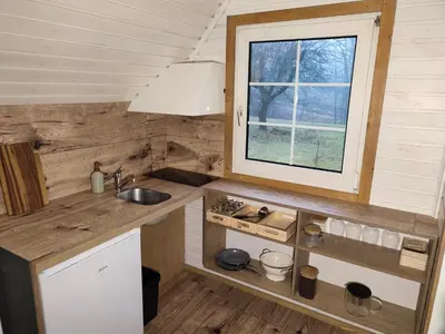 a kitchen in a tiny house with a window at Užukalnio sodyba in Užuguostis