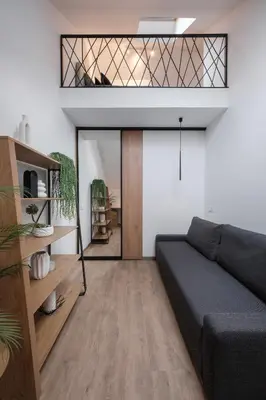 a living room with a couch and a glass door at Butas-loftas mieste, Kaunas in Kaunas