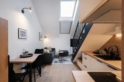 a kitchen and living room in a loft with a staircase at Butas-loftas mieste, Kaunas in Kaunas