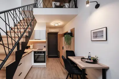 a kitchen and dining room with a staircase in a house at Butas-loftas mieste, Kaunas in Kaunas
