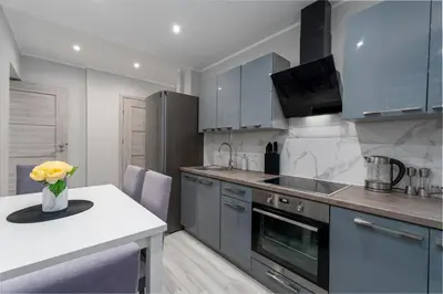a kitchen with blue cabinets and a vase of flowers on a counter at Stylish Apartment For up to 4 Guests With WiFi, Free Parking in Vilkaviškis