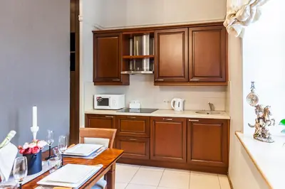a kitchen with wooden cabinets and a wooden table with a dining room at Central apartments 2 x Free Parking x SELF CHECK-IN 24h by H&H in Vilnius