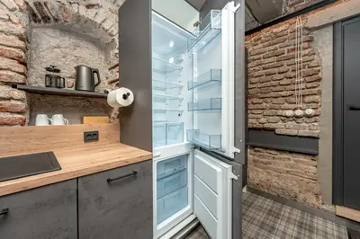 a kitchen with an open refrigerator and a brick wall at Historic Bliss In Vilnius Old Town in Vilnius
