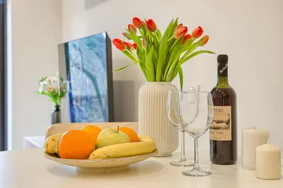 a table with a bowl of fruit and a bottle of wine at Business-class apartments 2 x Free Parking x SELF CHECK IN 24x7 in Vilnius