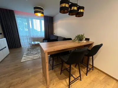 a dining room with a wooden table and chairs at Apartamentai JOLA in Vilkaviškis