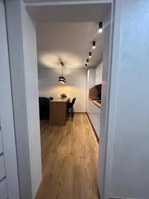a hallway leading to a kitchen with a table in a room at Apartamentai JOLA in Vilkaviškis