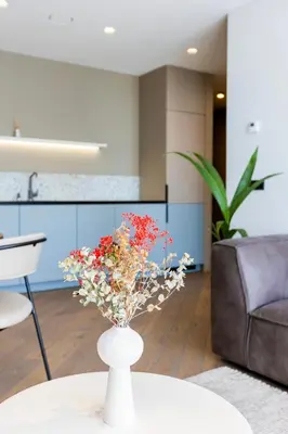 a vase with flowers on a table in a living room at Brand New Central Panorama (SELF CHECK-IN) in Vilnius