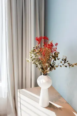 a white vase with red flowers on a table at Brand New Central Panorama (SELF CHECK-IN) in Vilnius