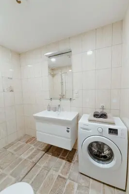 a bathroom with a washing machine and a sink at New Modern studio apartment next to the city centre in Vilnius