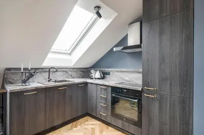 a kitchen with wooden cabinets and a skylight at Cozy Penthouse in Vilnius