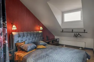a bedroom with a bed and a red wall at Cozy Penthouse in Vilnius
